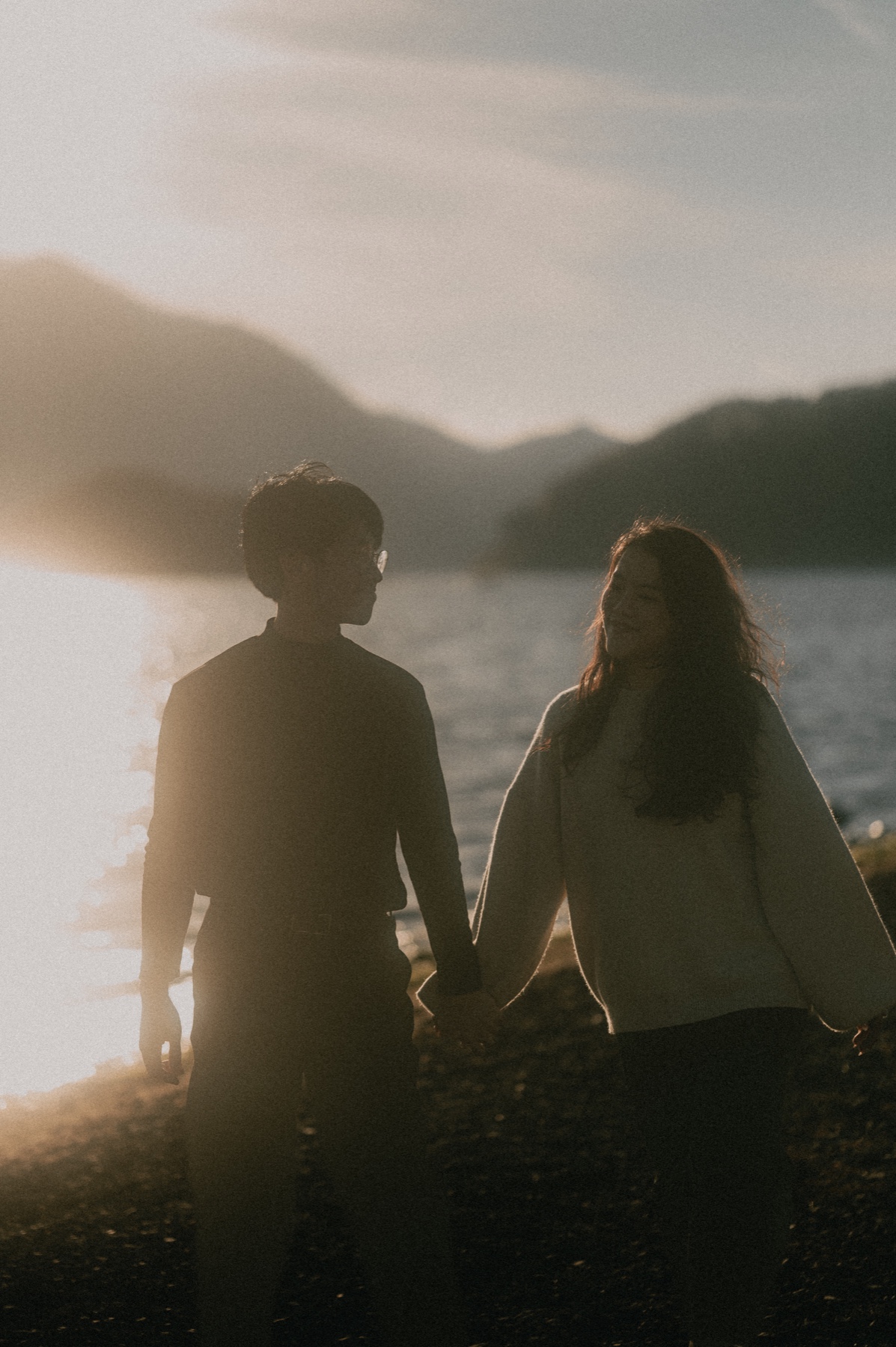 Xuan Le and Tracy holding hands beside the water at sunset